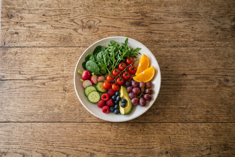 Plato con verduras, frutas y aguacate sobre una mesa de madera